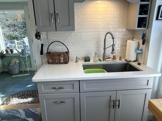 kitchen with tile patterned flooring, sink, gray cabinets, light stone counters, and tasteful backsplash