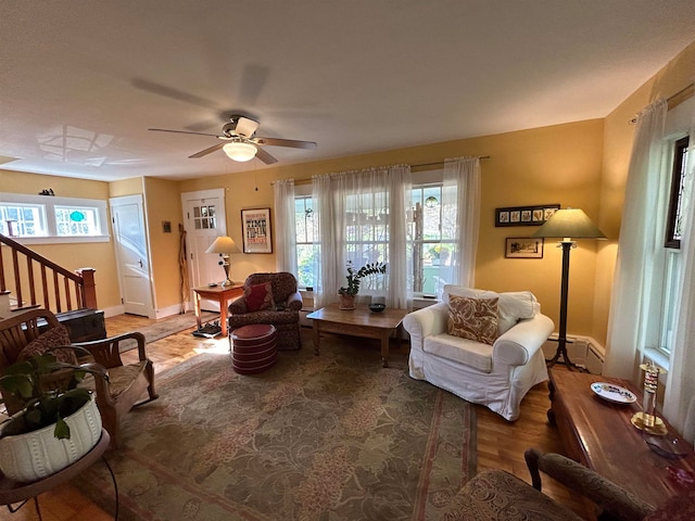 living room with ceiling fan, wood-type flooring, and a baseboard heating unit