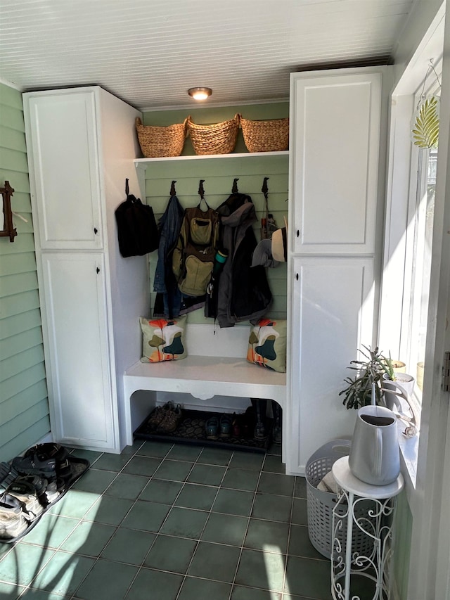 mudroom with dark tile patterned floors and wood walls