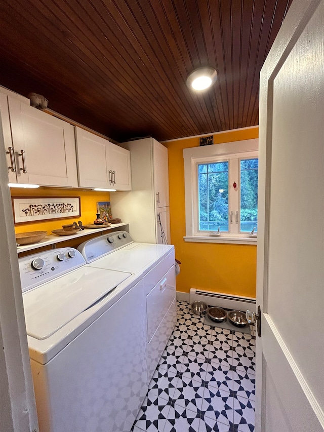 clothes washing area featuring baseboard heating, washer and dryer, wood ceiling, and cabinets