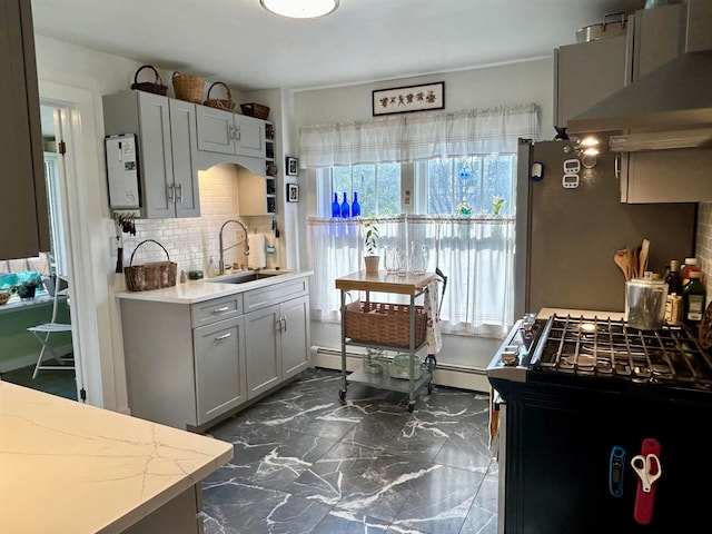 kitchen featuring sink, baseboard heating, gray cabinets, decorative backsplash, and ventilation hood