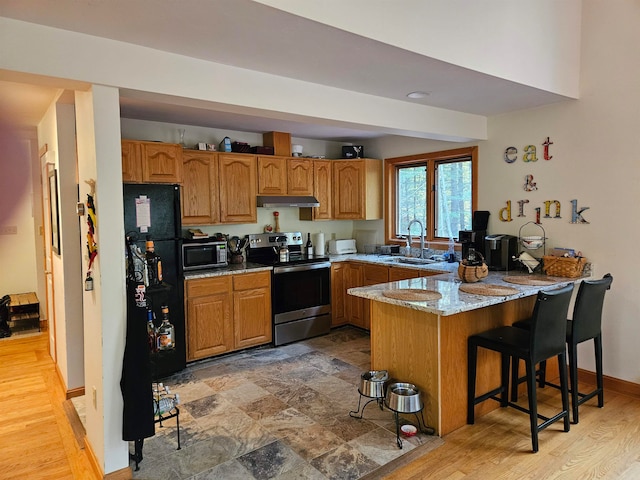 kitchen featuring appliances with stainless steel finishes, kitchen peninsula, light hardwood / wood-style flooring, and sink