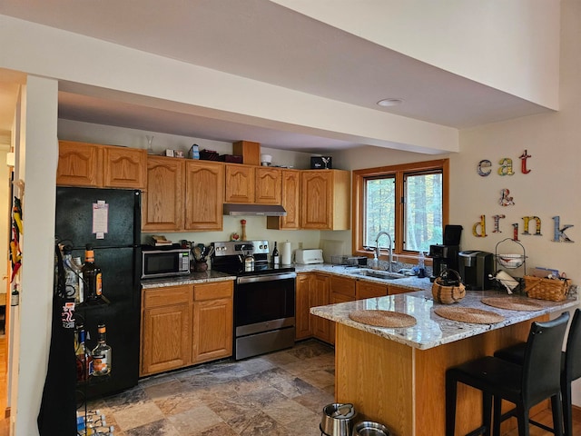 kitchen featuring black fridge, kitchen peninsula, sink, stainless steel electric range, and light stone counters