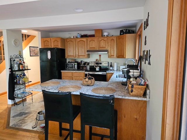 kitchen with sink, light stone countertops, stainless steel appliances, and light wood-type flooring