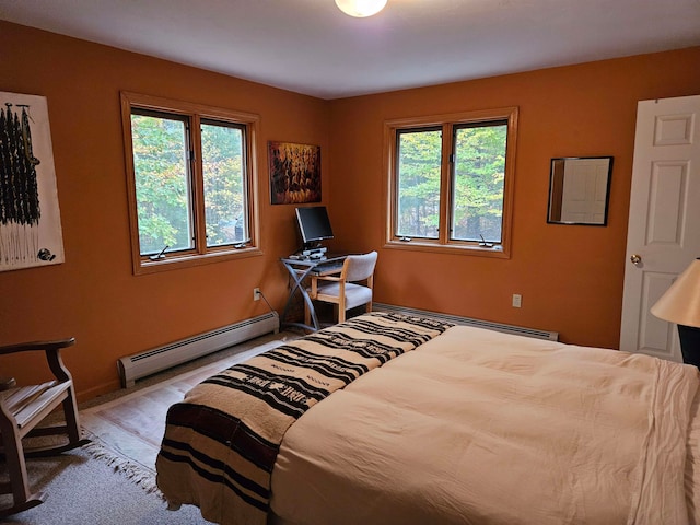 bedroom with light hardwood / wood-style floors and a baseboard heating unit