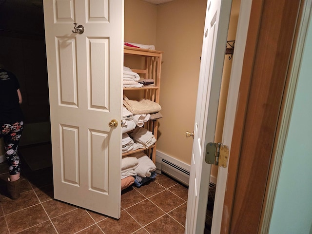 spacious closet featuring dark tile patterned flooring and a baseboard heating unit