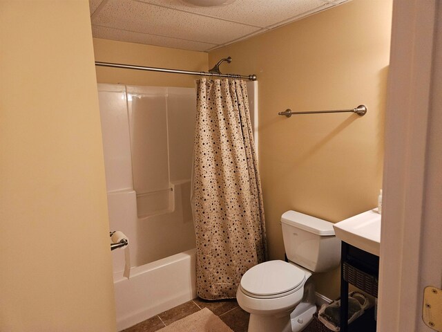 full bathroom with a paneled ceiling, toilet, vanity, shower / tub combo with curtain, and tile patterned flooring