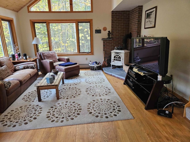 living room with hardwood / wood-style flooring, a wood stove, lofted ceiling, and a baseboard heating unit