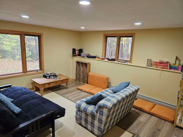 living room with a baseboard heating unit and light wood-type flooring