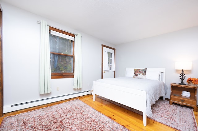 bedroom featuring wood-type flooring and a baseboard radiator