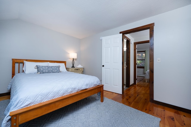 bedroom with vaulted ceiling and hardwood / wood-style flooring