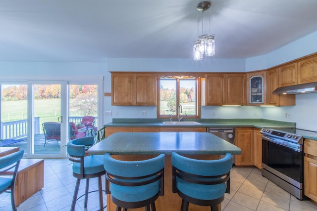 kitchen with light tile patterned floors, a breakfast bar area, sink, pendant lighting, and stainless steel appliances