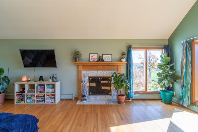 living room with a baseboard radiator, hardwood / wood-style flooring, lofted ceiling, and a fireplace