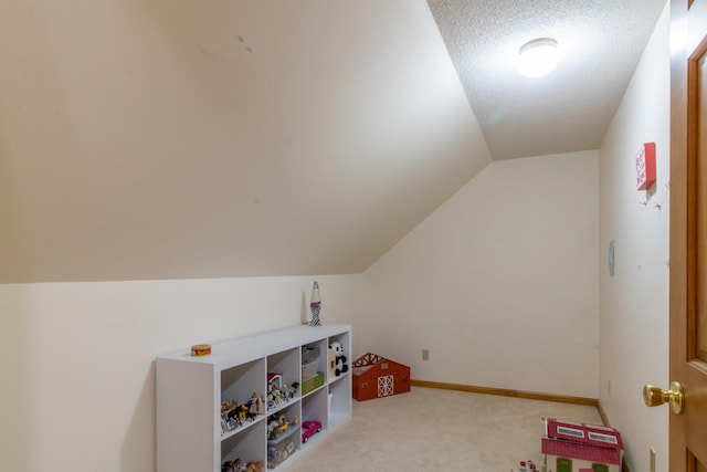 playroom with light carpet, a textured ceiling, and vaulted ceiling