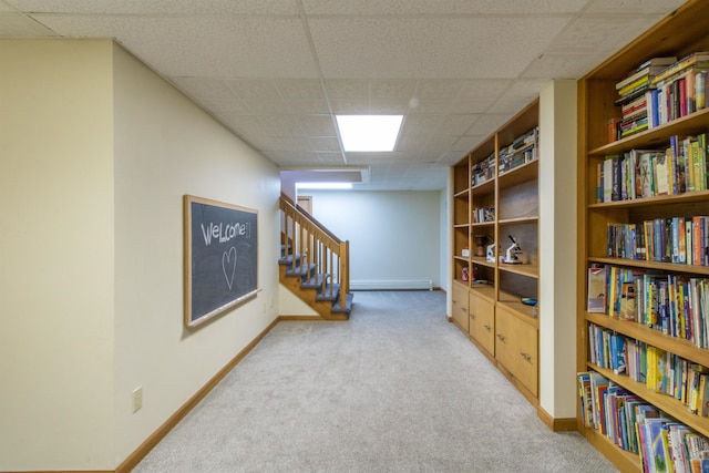 basement featuring a drop ceiling and light colored carpet