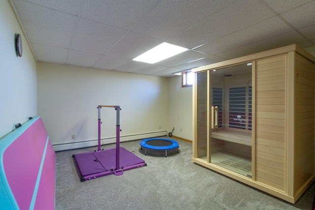 workout room with a paneled ceiling, a baseboard radiator, and carpet floors