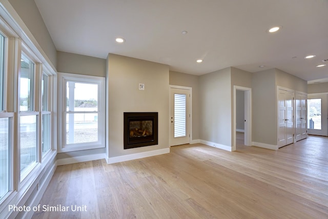 unfurnished living room with light hardwood / wood-style flooring and a wealth of natural light