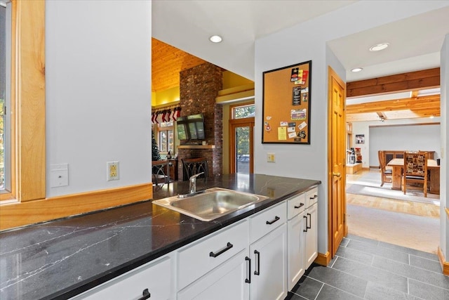 kitchen with dark hardwood / wood-style flooring, sink, a brick fireplace, and white cabinets