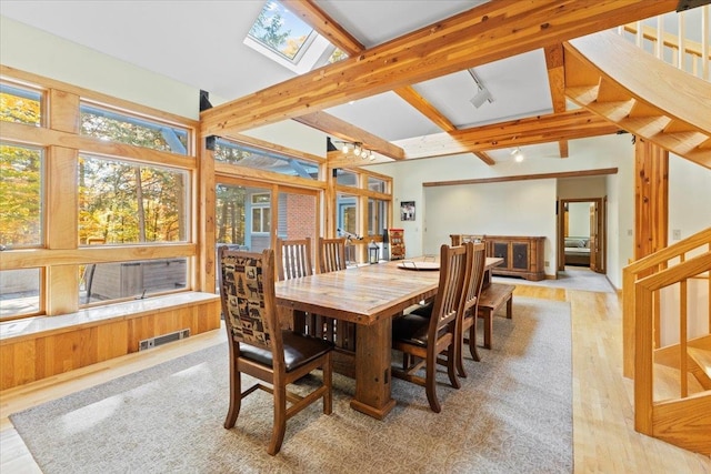 dining area with light hardwood / wood-style floors and lofted ceiling with skylight