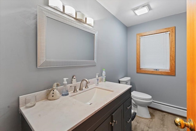 bathroom with vanity, toilet, wood-type flooring, and baseboard heating