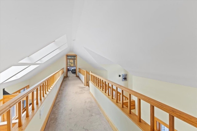 corridor with lofted ceiling with skylight and carpet floors