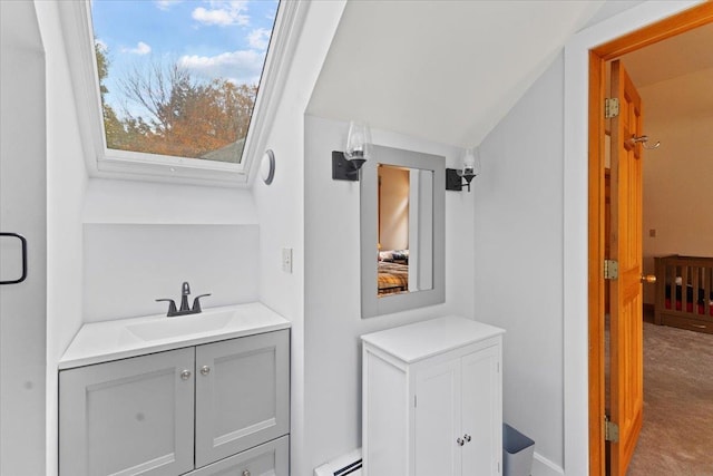 bathroom featuring baseboard heating, vanity, and lofted ceiling