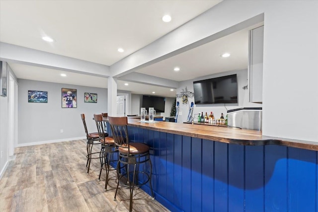 bar with butcher block counters and light wood-type flooring