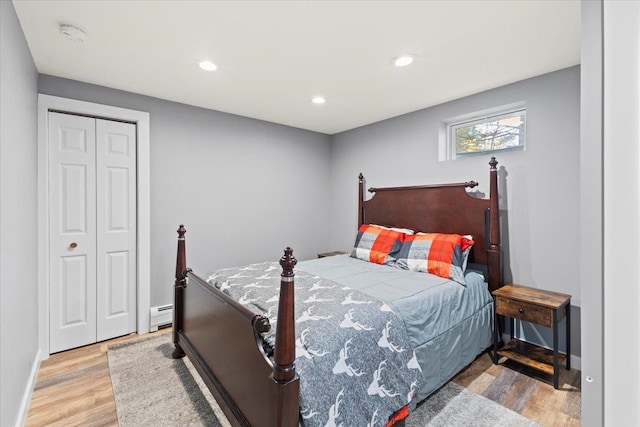 bedroom with light hardwood / wood-style floors, a closet, and a baseboard radiator