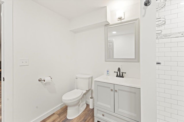 bathroom with vanity, toilet, a tile shower, and hardwood / wood-style floors