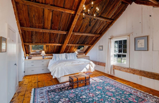 bedroom featuring vaulted ceiling with beams, light hardwood / wood-style flooring, wooden ceiling, a notable chandelier, and wood walls
