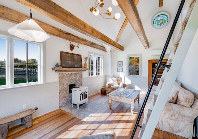 living room with vaulted ceiling with beams, a wood stove, and wood-type flooring