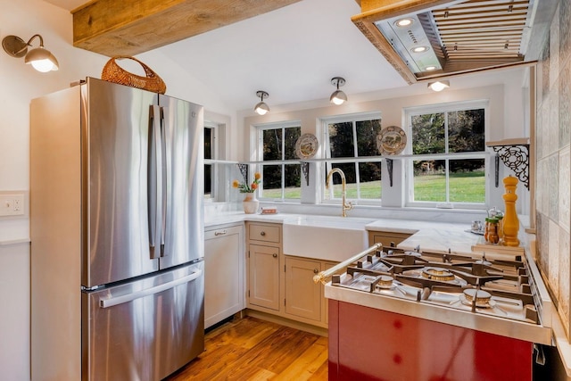 kitchen featuring appliances with stainless steel finishes, lofted ceiling with beams, sink, and light wood-type flooring