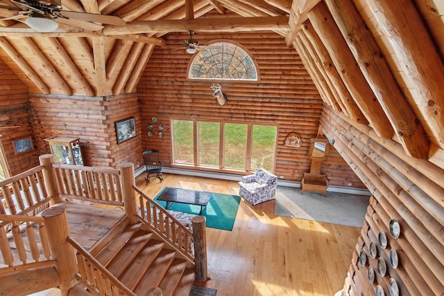 living room with a baseboard radiator, log walls, wood-type flooring, and vaulted ceiling