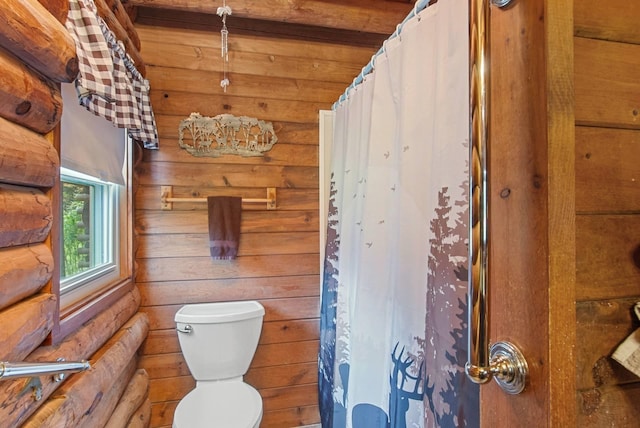 bathroom featuring rustic walls, a shower with curtain, and toilet