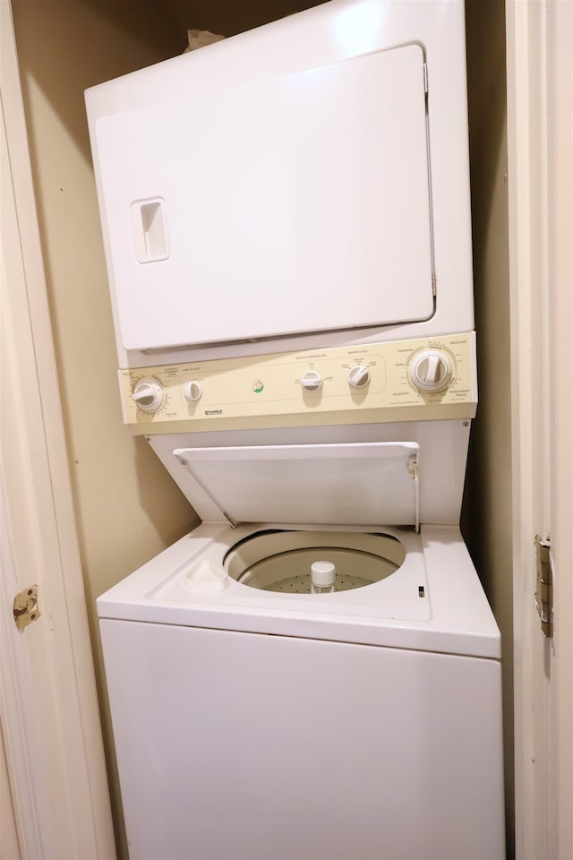 clothes washing area with stacked washing maching and dryer