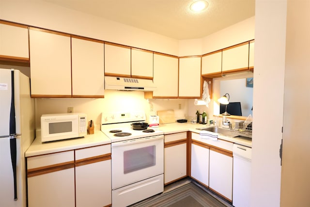 kitchen featuring a textured ceiling, cream cabinets, sink, and white appliances