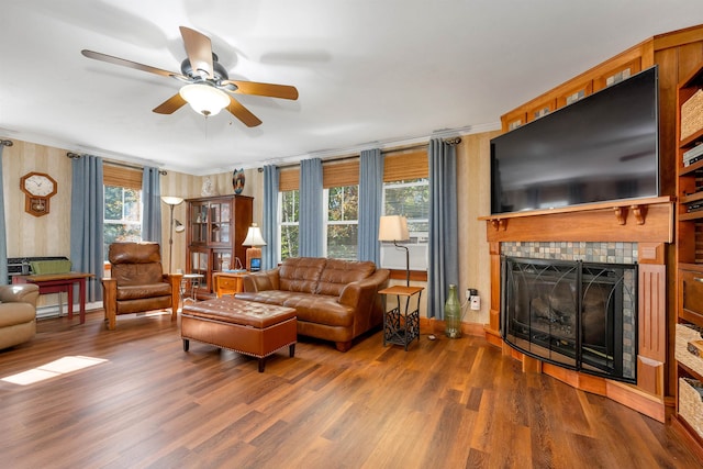 living room with ceiling fan, a fireplace, dark wood-type flooring, and ornamental molding