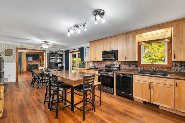 kitchen with black appliances, a breakfast bar, dark hardwood / wood-style flooring, and sink