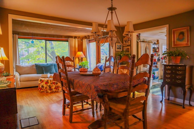 dining room featuring a notable chandelier, wood-type flooring, and beamed ceiling