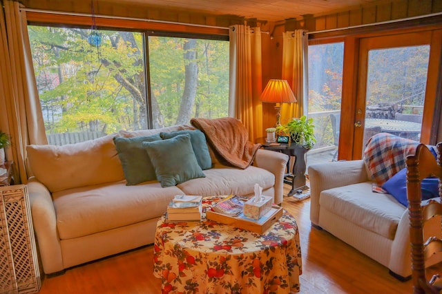 living room with light hardwood / wood-style floors, wood ceiling, and wooden walls