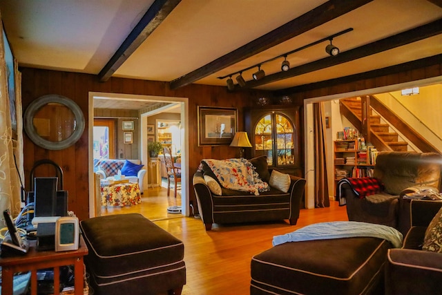 interior space with rail lighting, beamed ceiling, wooden walls, and light hardwood / wood-style floors