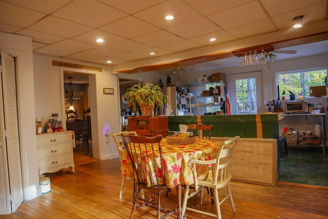 dining room featuring a paneled ceiling, light wood-type flooring, and ceiling fan