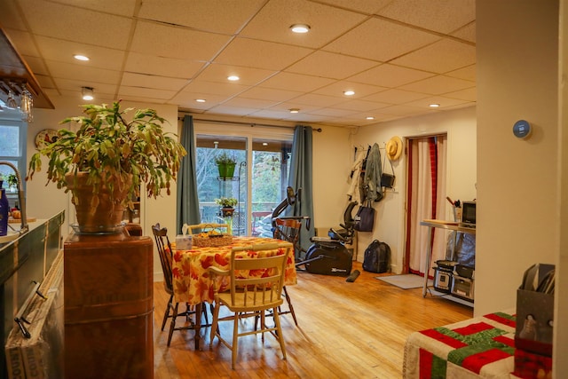 dining space with light hardwood / wood-style flooring and a paneled ceiling