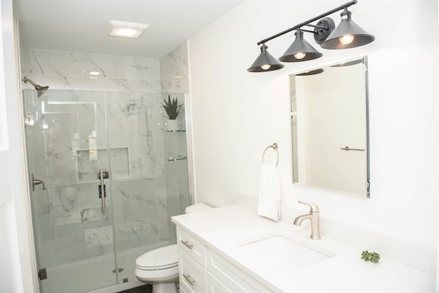 bathroom featuring toilet, vanity, and a shower with door