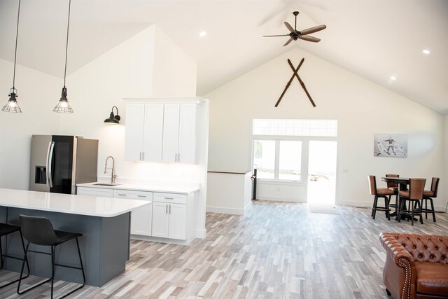 kitchen with white cabinets, hanging light fixtures, stainless steel fridge with ice dispenser, high vaulted ceiling, and light wood-type flooring