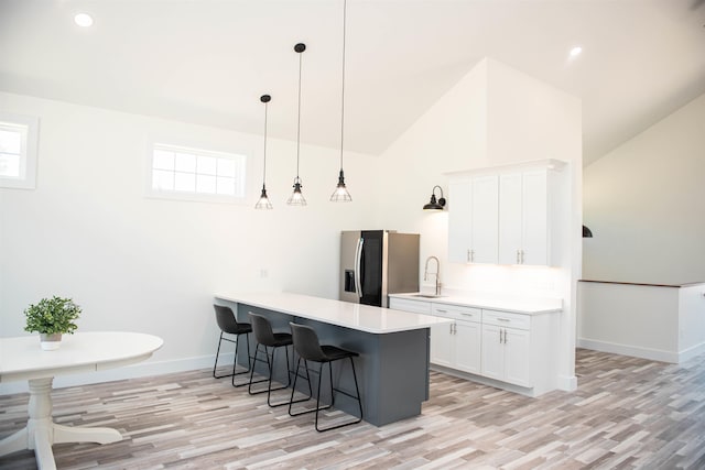 kitchen with light hardwood / wood-style floors, stainless steel refrigerator with ice dispenser, plenty of natural light, and white cabinets