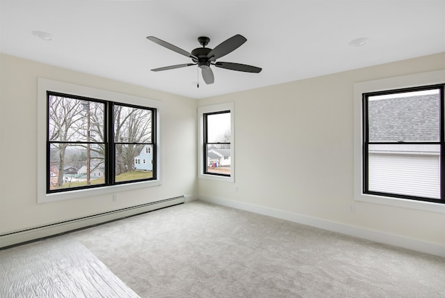 spare room featuring a baseboard heating unit, light colored carpet, and ceiling fan