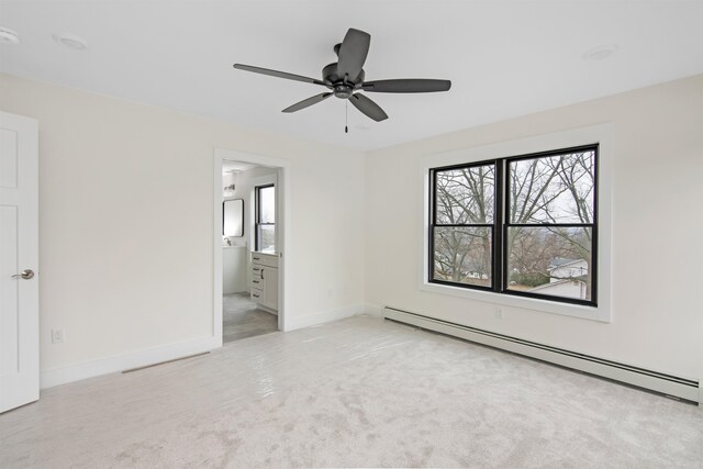 unfurnished bedroom featuring baseboard heating, light colored carpet, connected bathroom, and ceiling fan