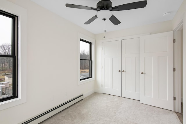 unfurnished bedroom featuring baseboard heating, light carpet, a closet, and ceiling fan