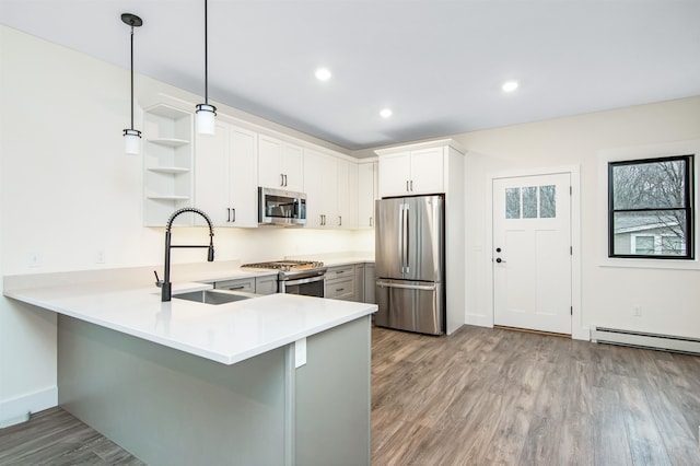 kitchen featuring appliances with stainless steel finishes, sink, kitchen peninsula, white cabinetry, and decorative light fixtures